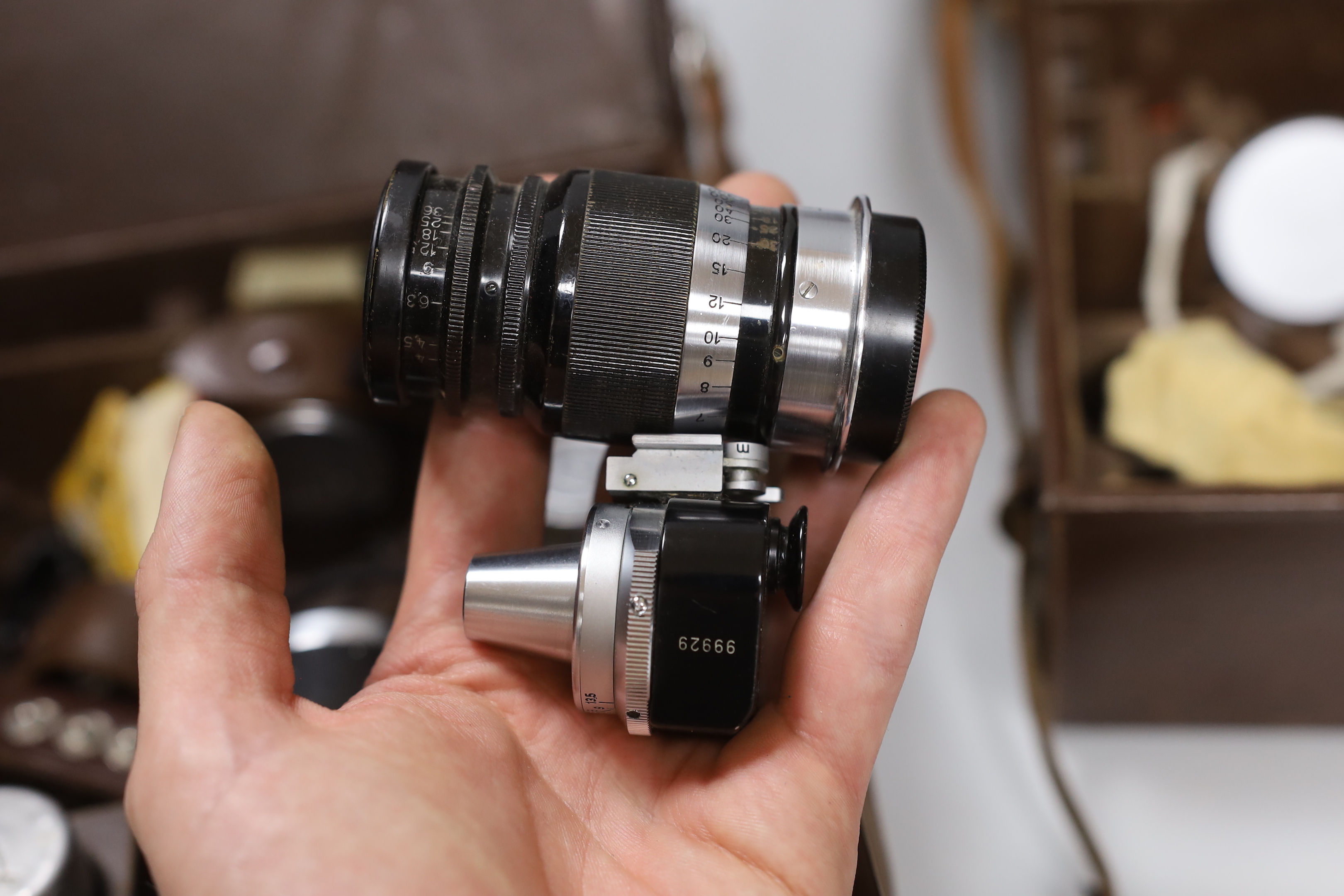 A collection of Leica etc camera accessories, including Leica film canisters, Leitz Elmer lenses and accessories, two Leica leather cases containing accessories in fitted compartments, three hardback Leica manuals, bookl